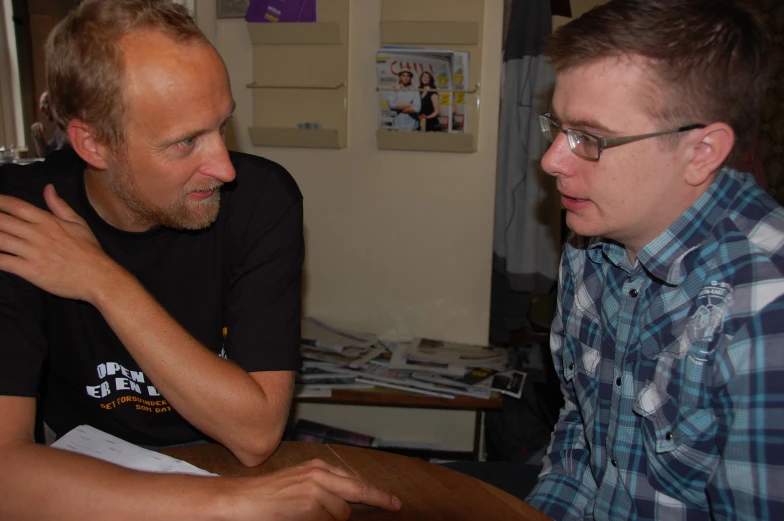 two men sit together while one holds his arm to the other