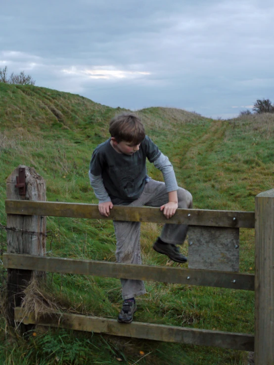 a child jumping up on a wooden fence