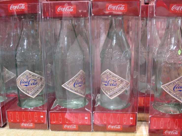 four coca cola bottles sitting inside of clear cases