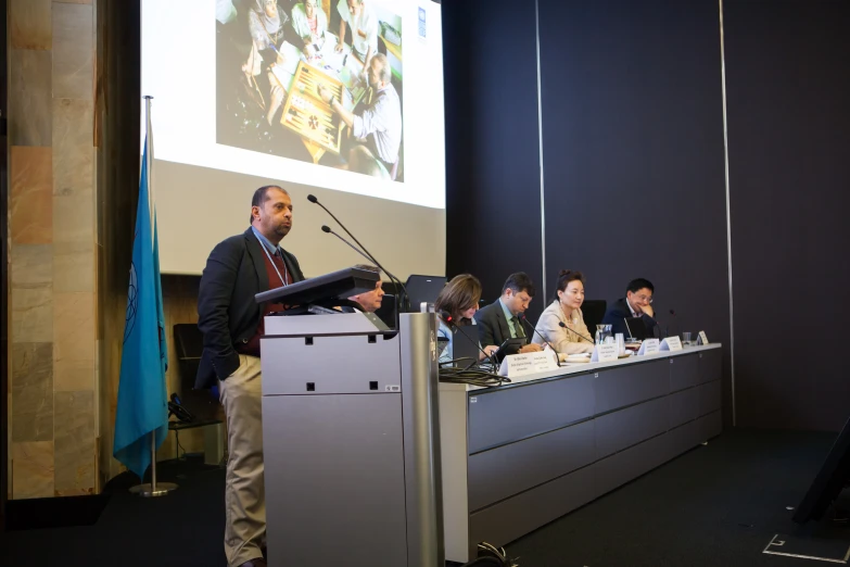 a group of people at a podium in front of a screen