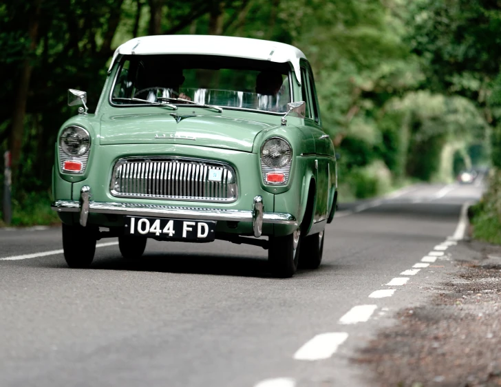 a small green car driving down the road