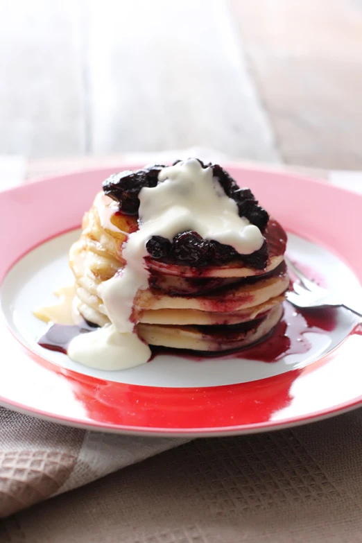 the pancakes with cream are on the pink plate