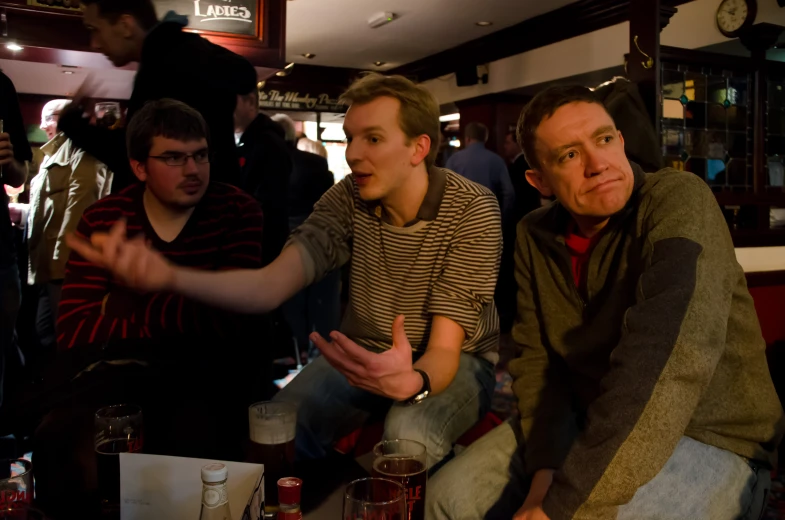 a group of men siting and drinking at a bar