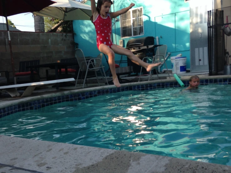 a  with arms outstretched in a swimming pool with her friends