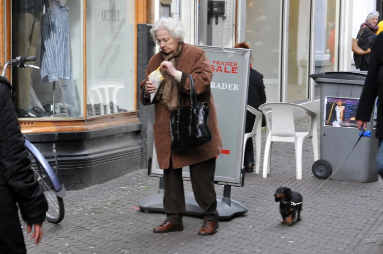 man holding bag while standing in street next to dog