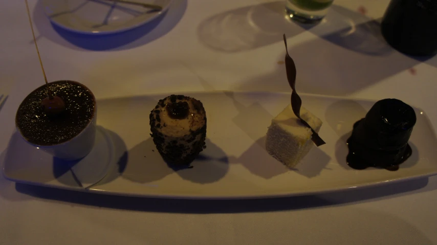 four desserts sit on a white plate on the table