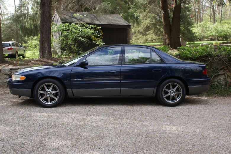 a car parked next to a tree with a shed in the background