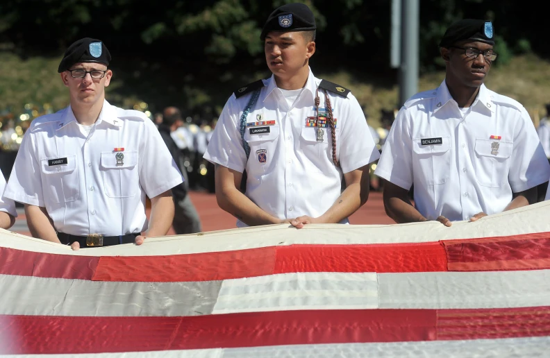 several men in white uniforms are holding an american flag