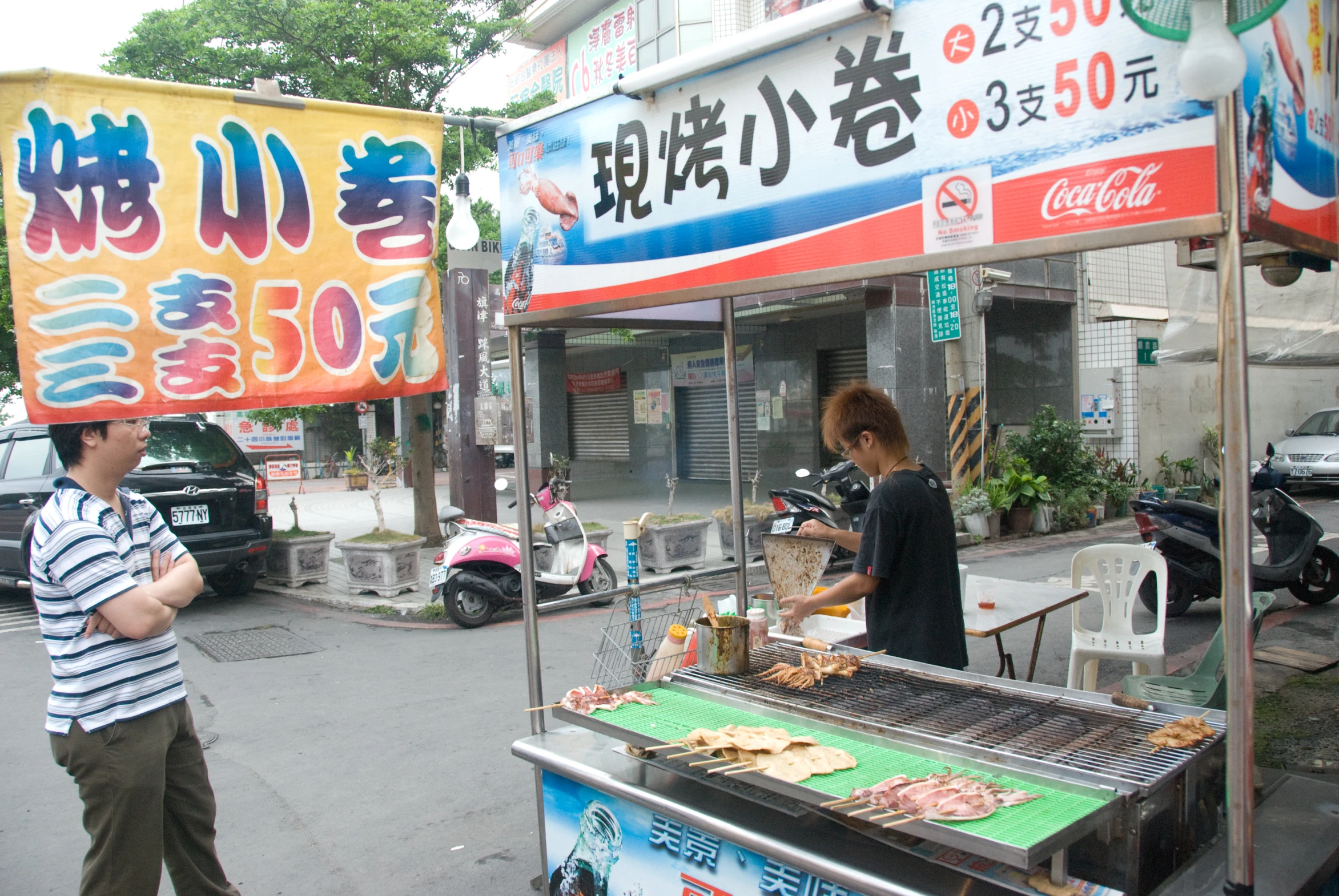 people stand outside at a grill with dogs on it