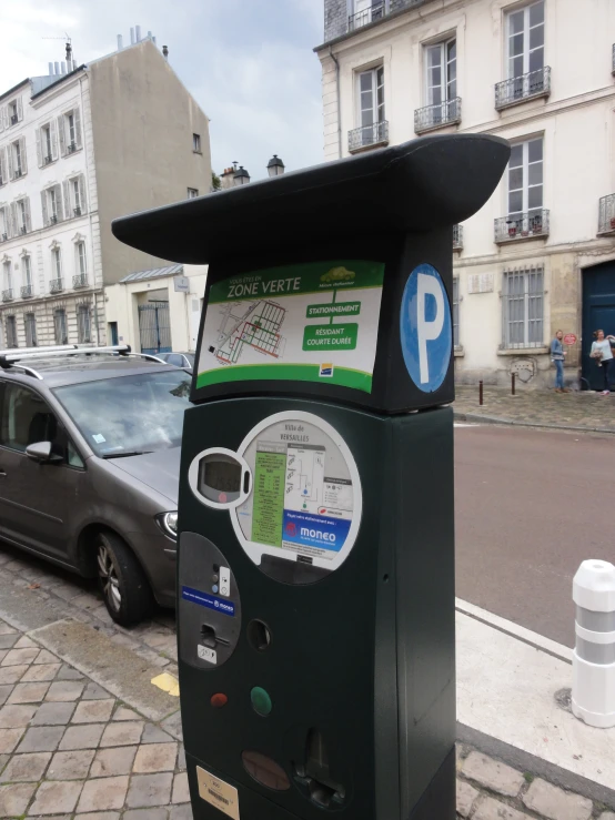 a parking meter on the sidewalk near parked cars