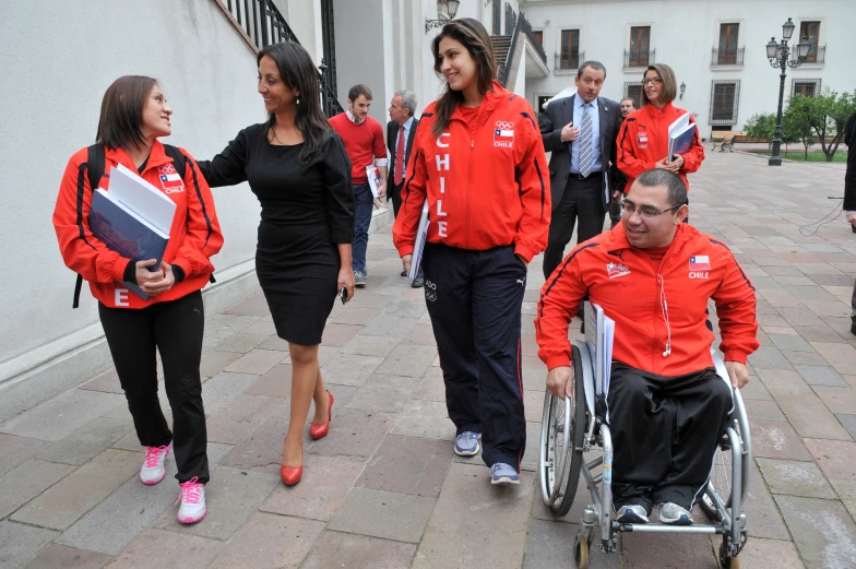 several people in red and black uniforms are walking along with one another