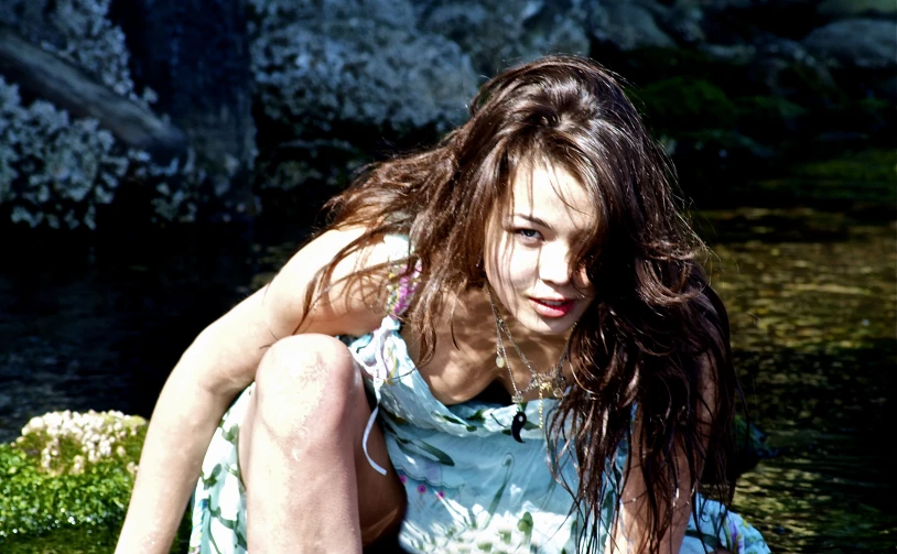 a woman leaning against the ground by some water