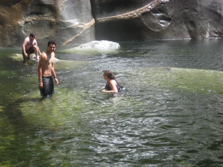 three people play in a pool of water