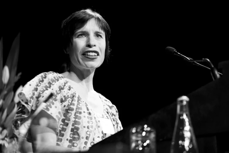 woman in patterned dress at a podium with a microphone