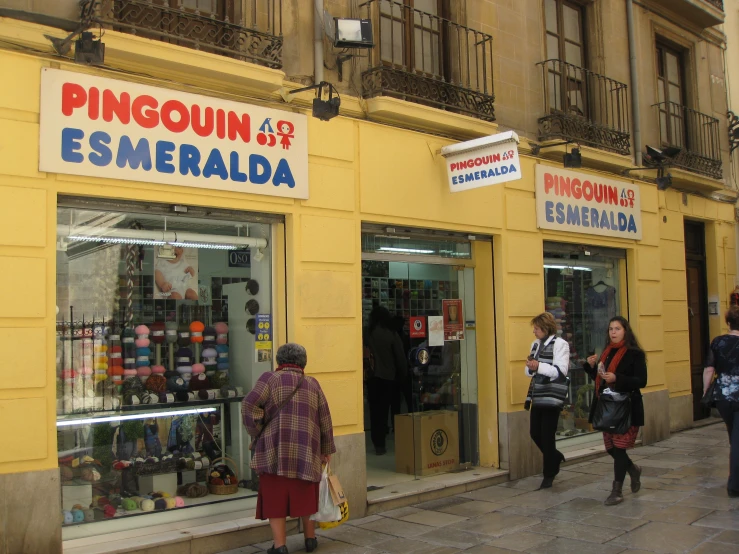 two people are walking by a shop on the street