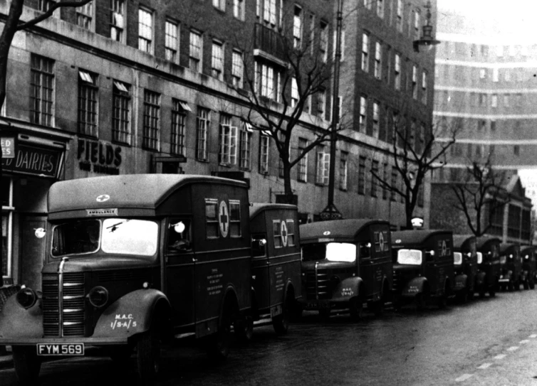 an old fashioned po of old trucks parked in a line in front of buildings