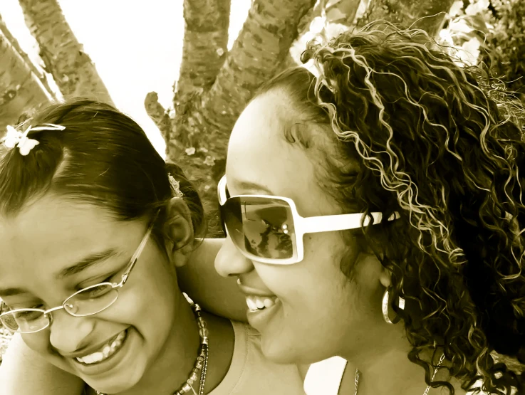 two women who are smiling under a tree