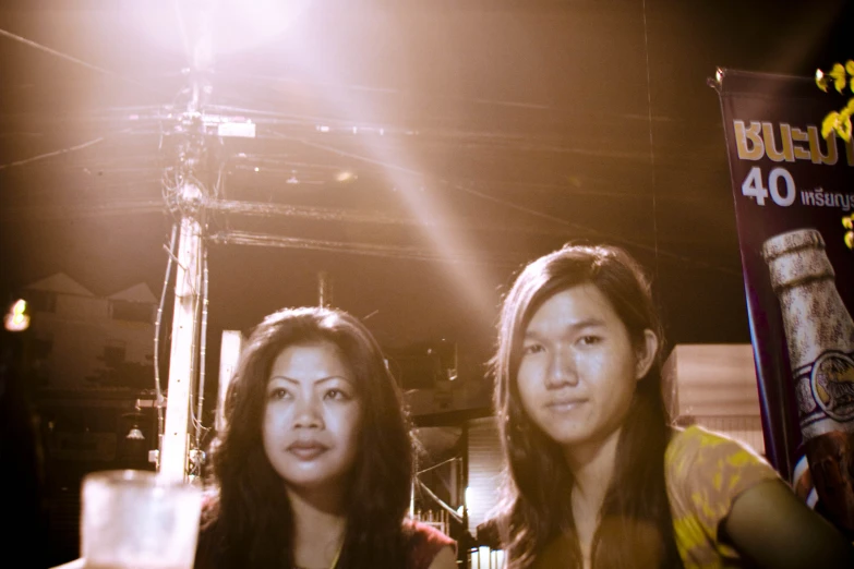 two young women sitting next to each other while holding up glasses