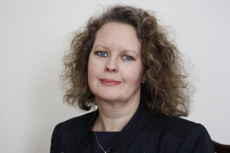 a woman with curly hair wearing a black jacket