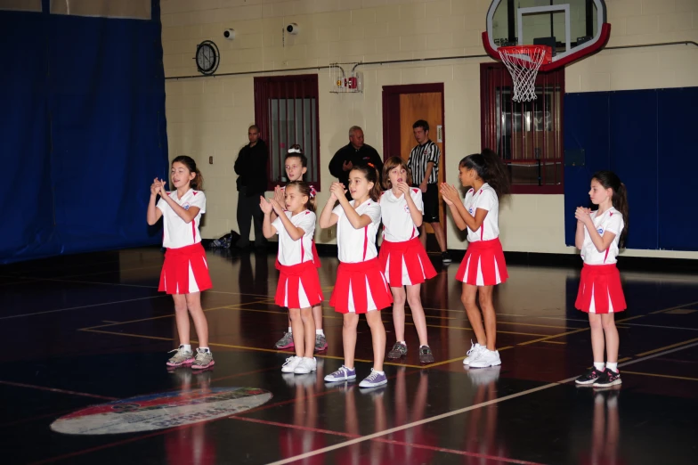 school s in uniform sing at the end of a basketball court