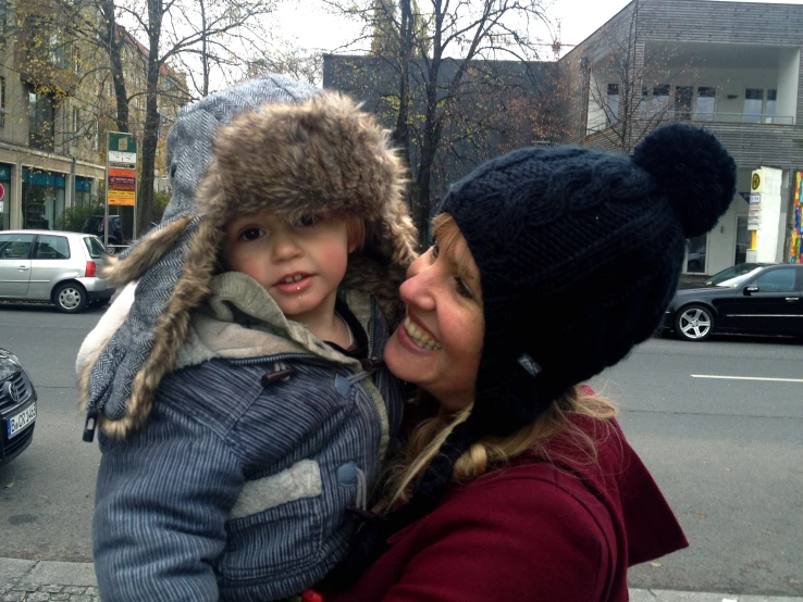 a mom wearing a winter hat smiles at her child