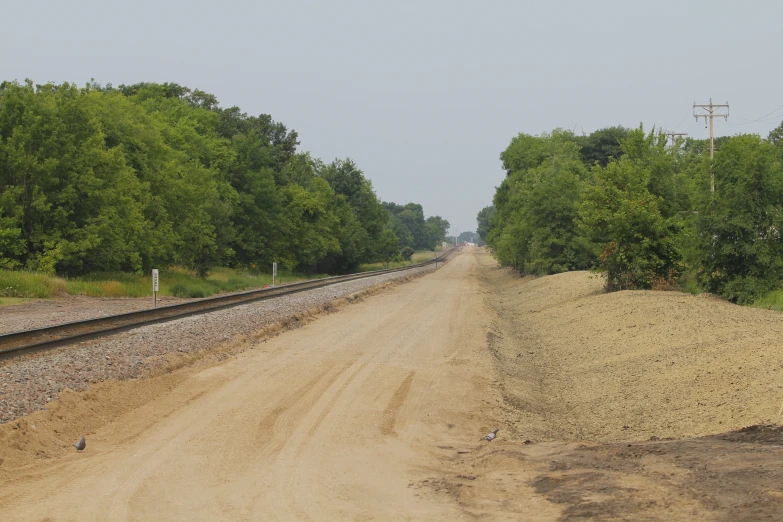 the road is made of dirt beside train tracks