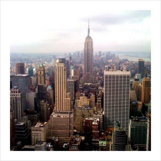 an aerial view of a city with buildings and clouds in the background