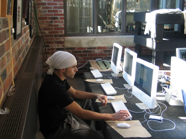 a man in a turban working on multiple computer screens