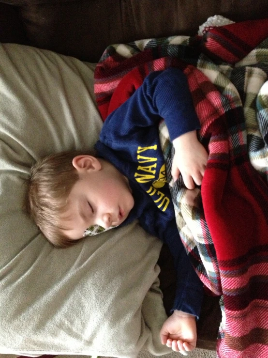 a little boy sleeps on his stomach while holding a pillow