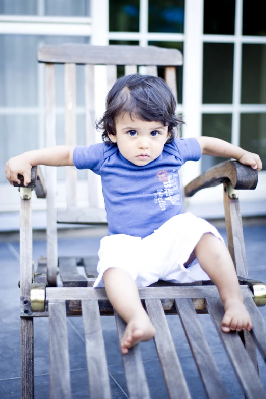 little girl sitting in an old - fashioned wooden rocking chair