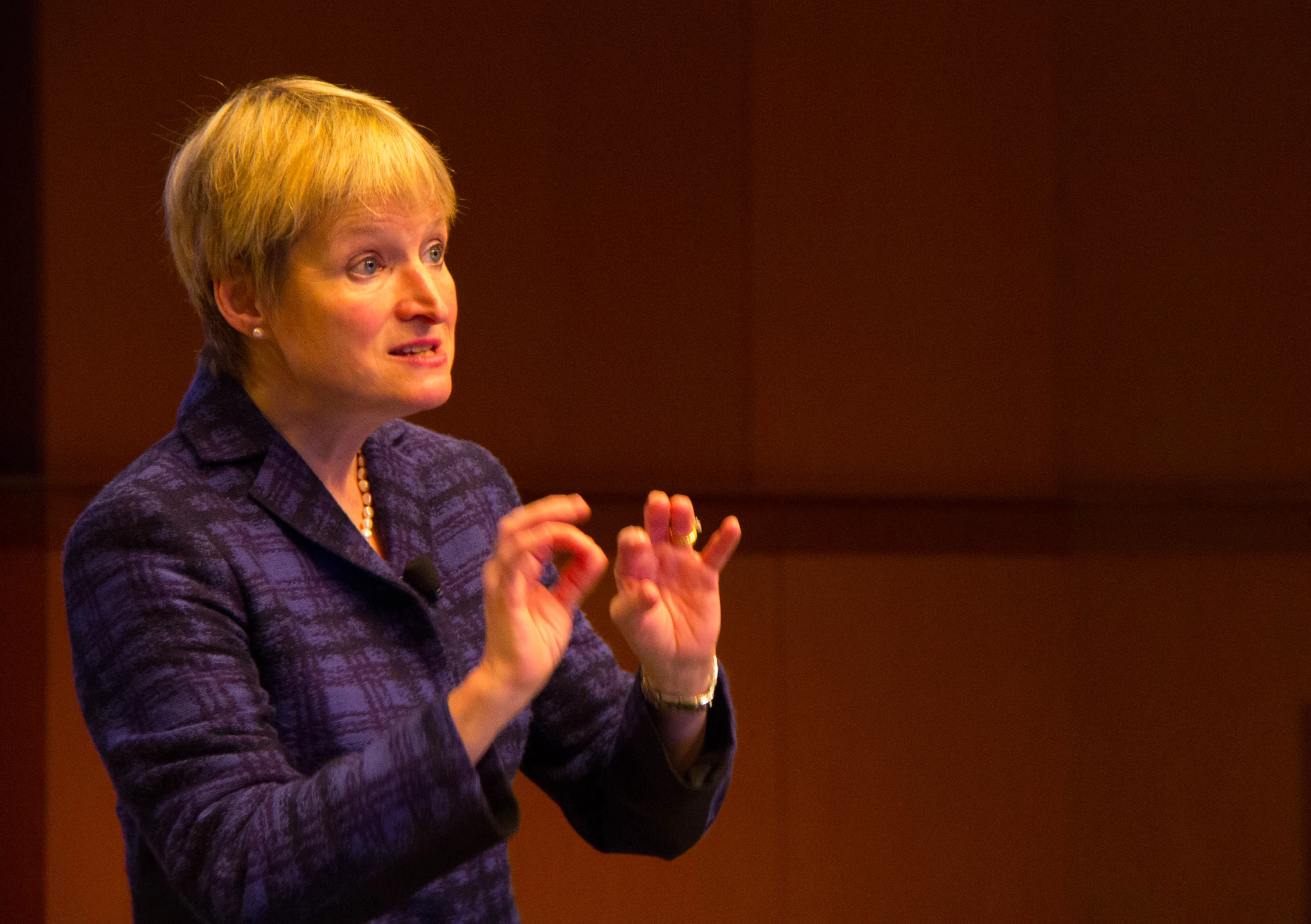 a woman in purple is making an announcement with her hands