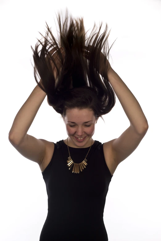 a woman smiling while holding her hair in one hand and wearing jewelry on the other