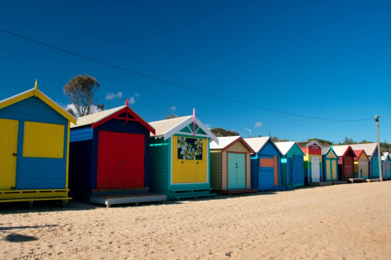 beach huts lined up on the sand with power lines above them