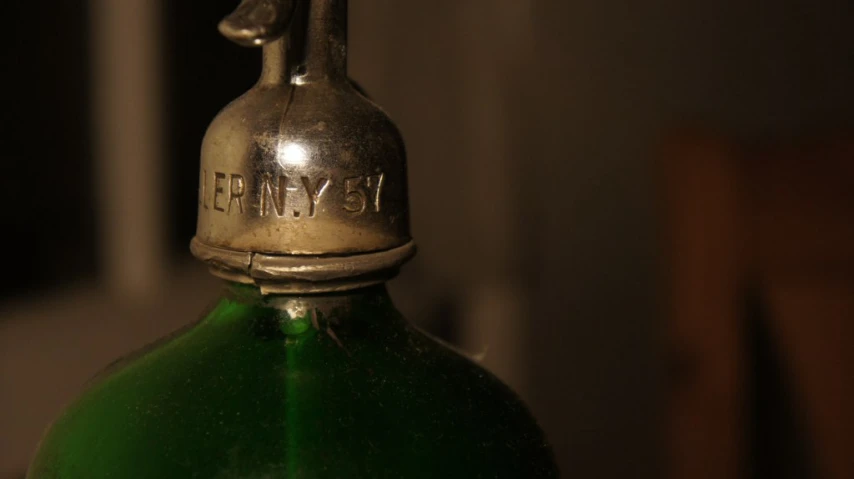 a close up of a green bottle with a tiny figure on it