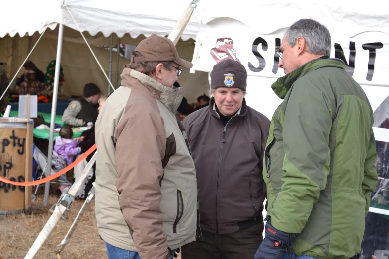 three men are standing in front of a tent