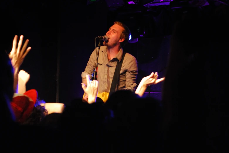 a man with a guitar standing in front of a microphone