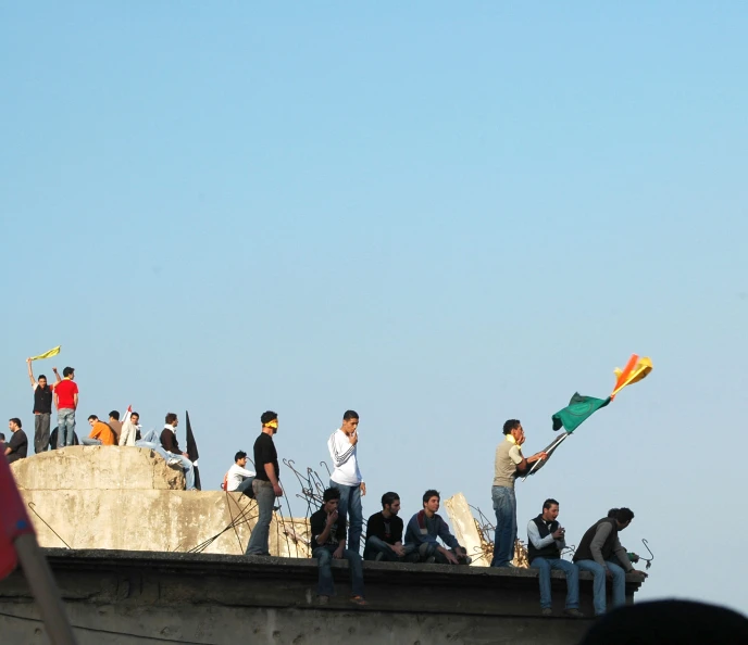 people are sitting on top of a cement structure while others stand on the side