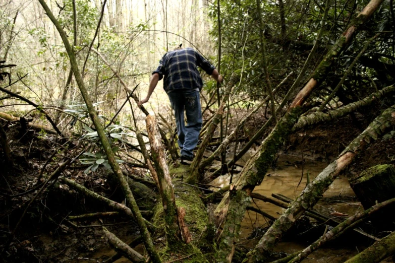 man in plaid shirt walking along muddy path