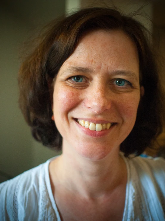 a woman in white shirt smiling at camera