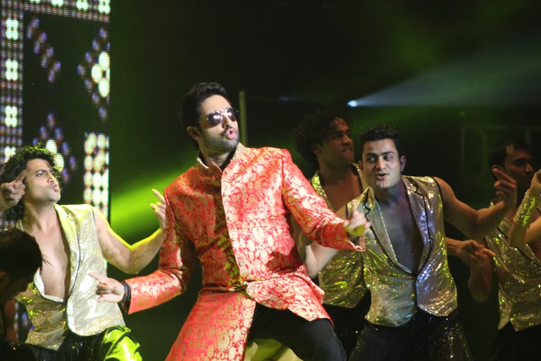 two men dressed in disco clothing performing on stage