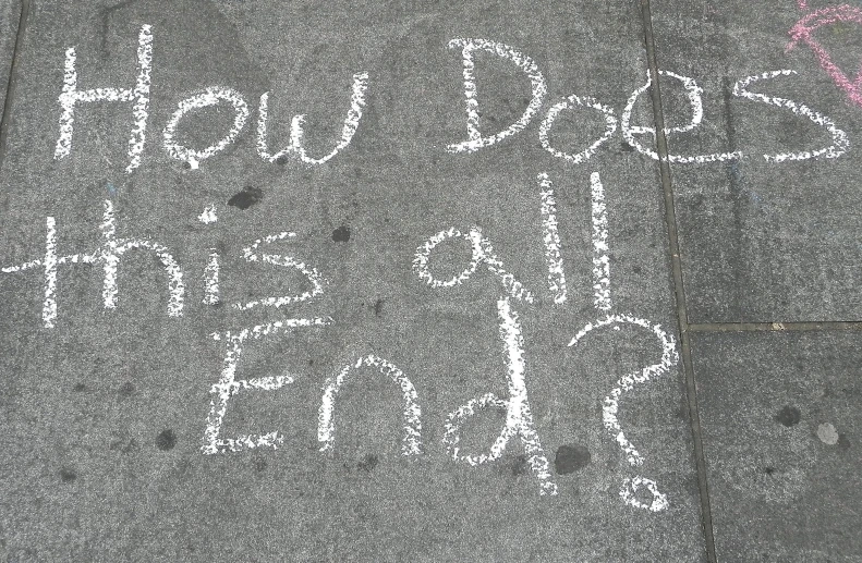 there is chalk written on the ground beside a sign