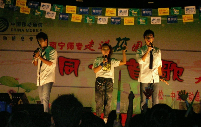 three men singing at a concert on stage