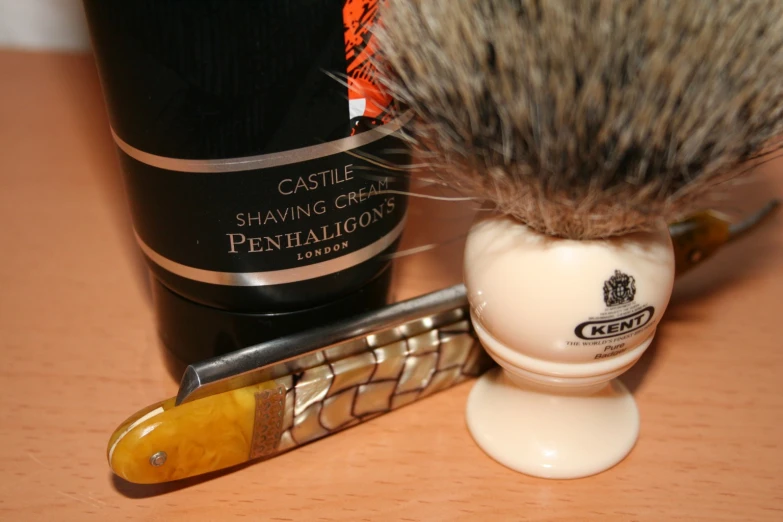 a razor and razor shaving brush sit beside a wine bottle