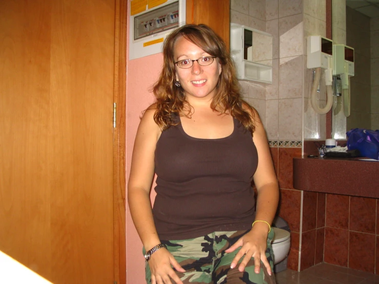 woman in glasses posing for picture in bathroom with sink