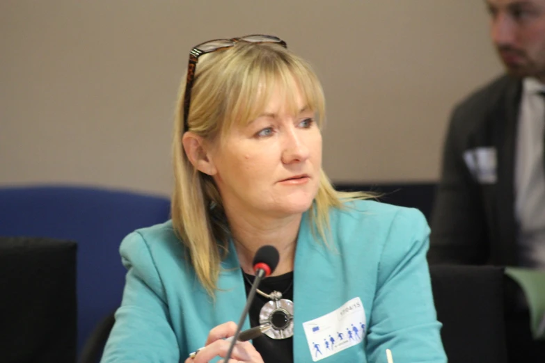 a lady speaking at a meeting using a microphone