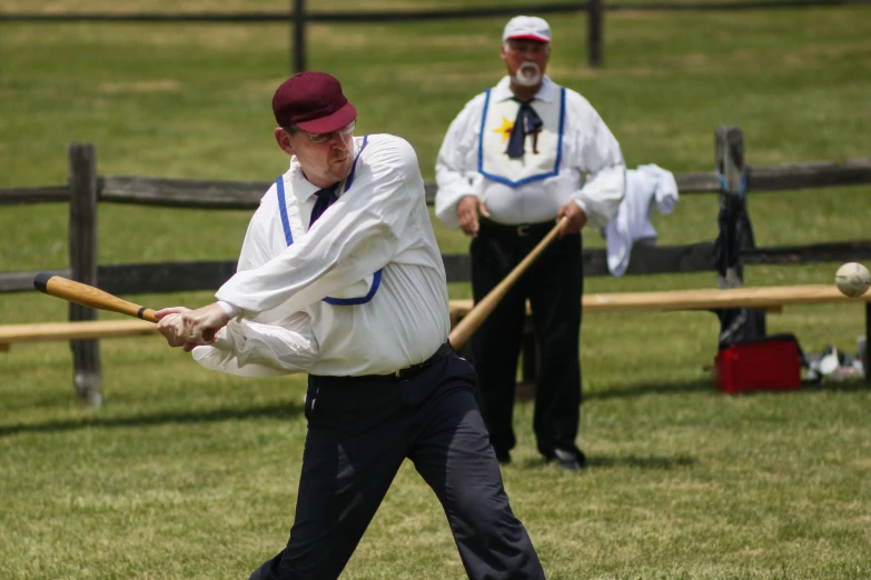 two people, two wearing shirts and one is swinging at a ball