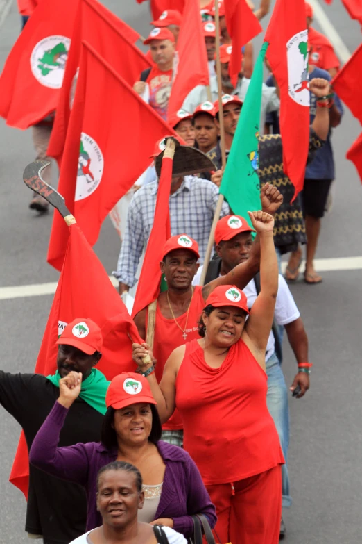 women in red dresses hold flags and salutes as they march through a street