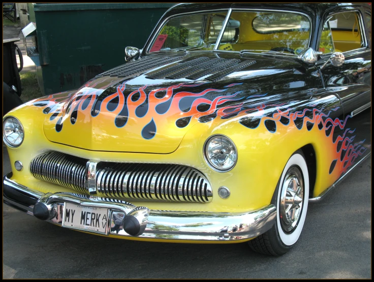 an old fashion  rod car with flames painted on it