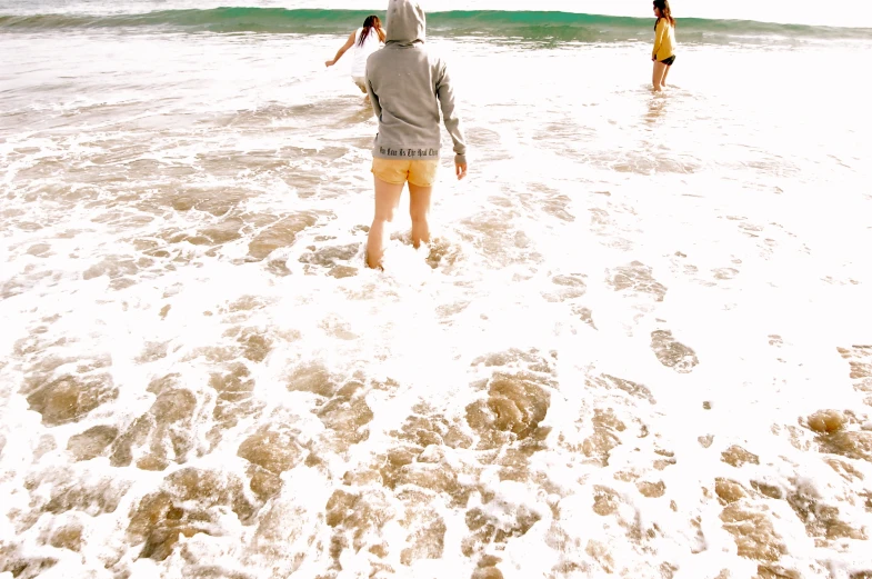 a girl and boy on the beach walking in the water