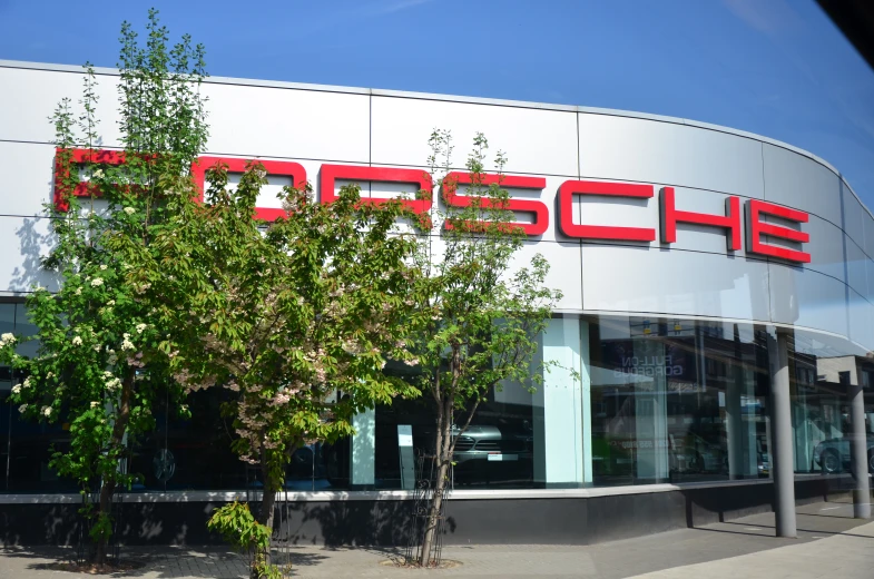 the front of a porsche dealership with trees outside